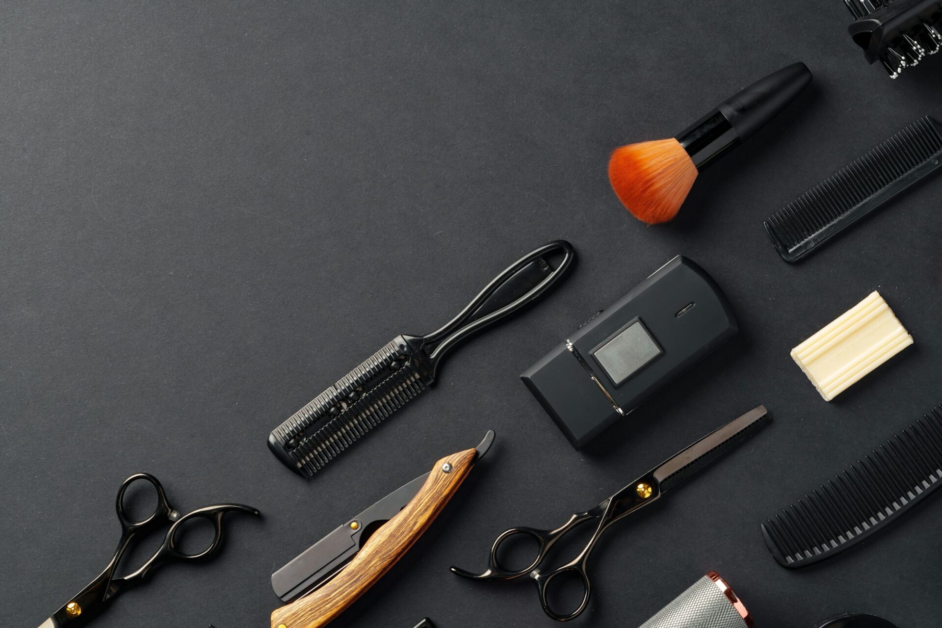 An Assortment of Professional Hairdressing Tools Laid Out on a Dark Surface