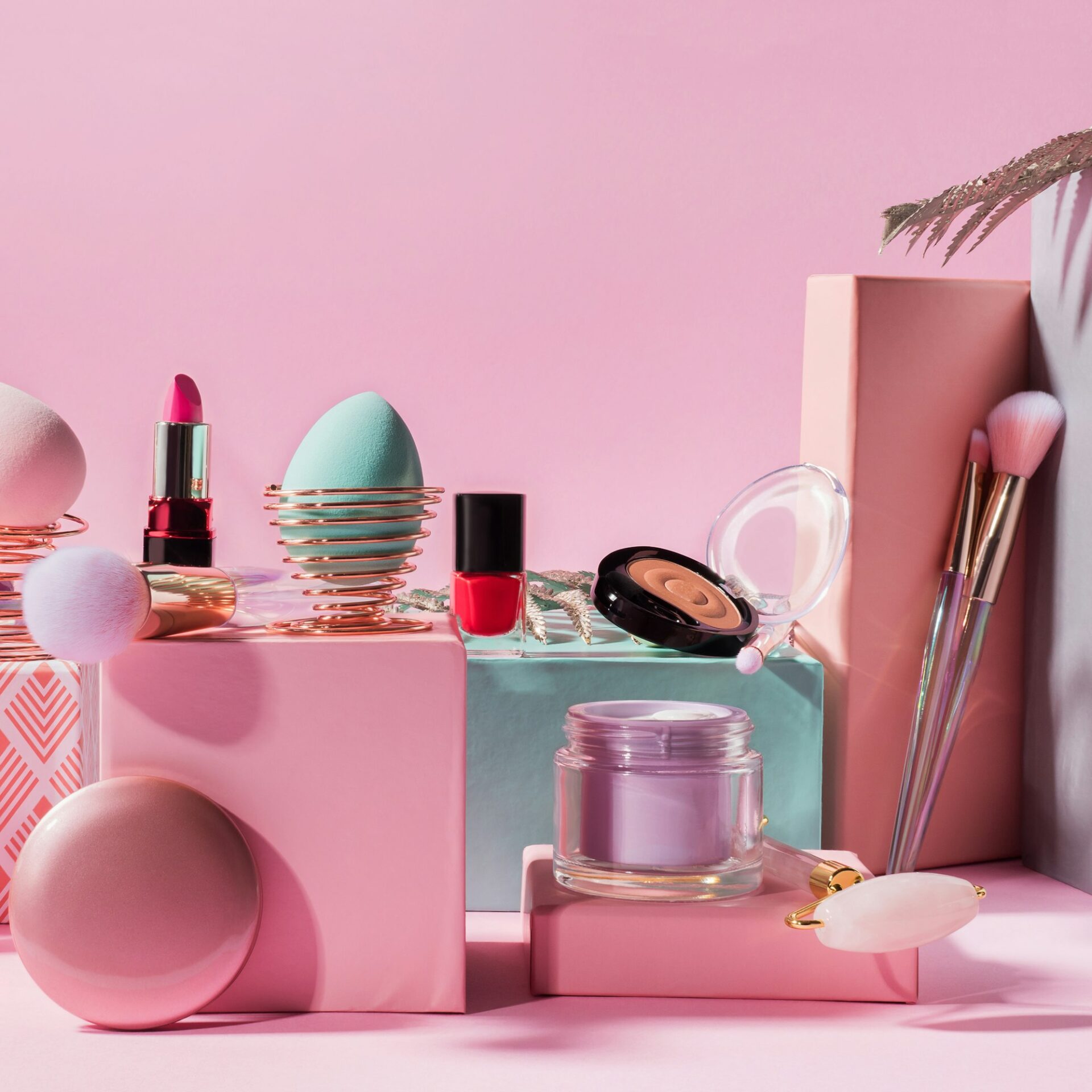 Make up tools, products on geometric podiums on pink